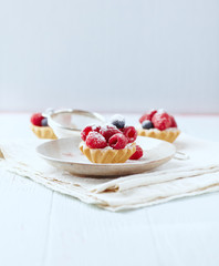 Little mascarpone tart with fresh raspberries on wooden background.