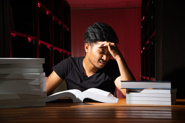 Portrait of black Thai Asian guy wear dark shirt make serious face reading a lot of book in red...