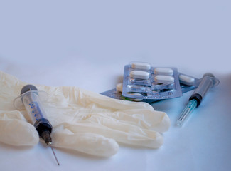 layout, on the glove lies a syringe and a blister with tablets. toned in blue