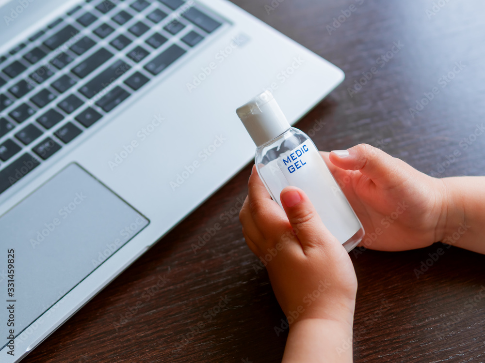 Wall mural self-isolation because of coronavirus outbreak. child is holding bottle of medical sanitizer gel for