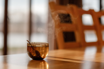 Cup of tea with steam on wooden table in the living room. selective focus