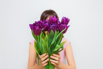 Young woman with purple flowers tulips in hands on white background.