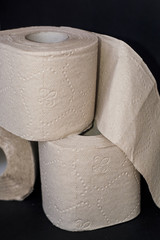 On black background, three piles of grey open toilet paper.