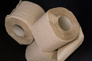 On black background, three piles of grey open toilet paper.