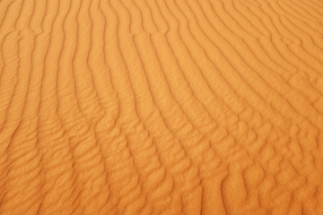 Bright saturated orange color desert sand wave patterns for warm summer background.