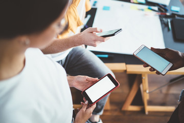 Faceless worker watching cellphone resting with partners in office