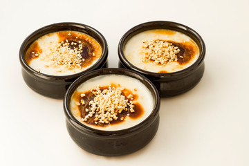 Traditional Turkish Style Baked Rice Pudding in casserole,clay dessert bowls with diced hazelnuts,on white surface.