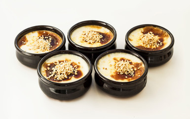 Traditional Turkish Style Baked Rice Pudding in casserole,clay dessert bowls with diced hazelnuts,on white surface.