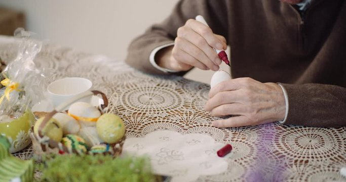 senior man painting easter egg