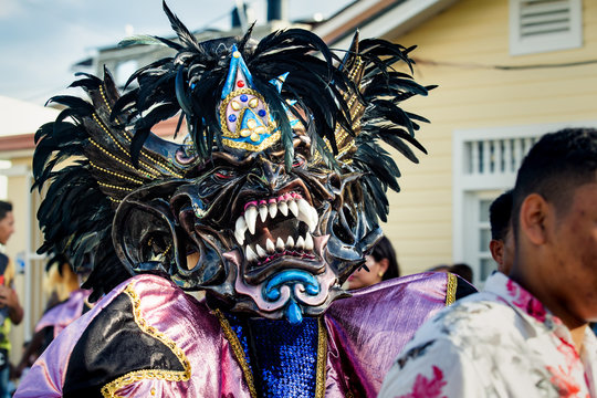 closeup man in original mask and costume poses for photo at dominican carnival