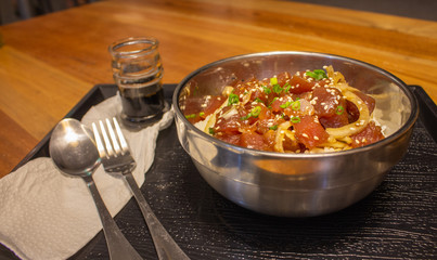 Traditional hawaiian meal called poke with fork, spoon and soy sause. Bowl of rice and raw chopped fish with onion. Asian cuisine. Raw salmon with rice. Tropical food in restaurant. Seafood concept.
