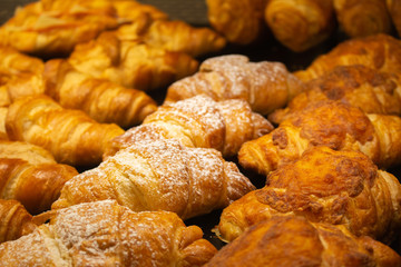 Tasty croissants in showcase. Bakery in golden color. Fresh baked french cakes. Pastry closeup. Delicious breakfast. Morning baking in cafe. Homemade cookery.