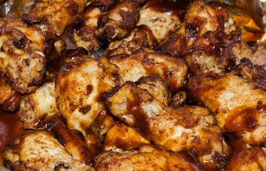 Baked chicken wings smothered in brown barbecue sauce. Full frame food and drink image. Take out restaurant and fast food.