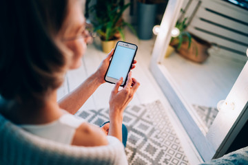 Woman watching cellphone in cozy apartment