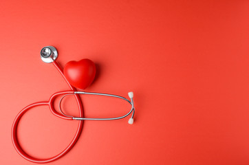 Red heart with stethoscope on red background.