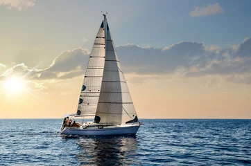 Fototapeten Nahaufnahme eines Segelboots, das unter einem wunderschönen Sonnenuntergang segelt © Image'in