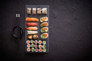 Sushi rolls set with salmon and tuna fish served on black stone board