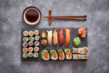 Composition of different kinds of sushi rolls placed on black stone board