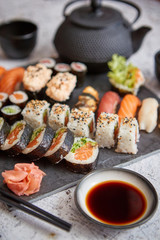 Assortment of different kinds of sushi rolls placed on black stone board