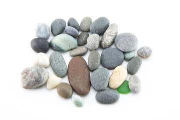 A pile of smooth multi-colored stones of small size and different colors on a white isolated background. Gray sea pebbles