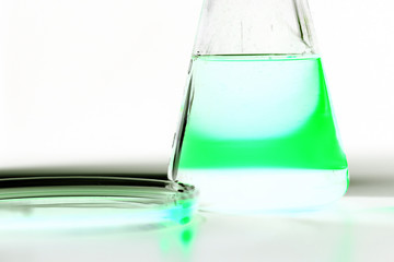 Petri dishand retort with green and blue with a chemical reagent. Chemical experiment with...