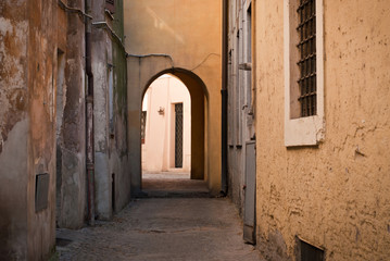 Fototapeta na wymiar A city street without people. A narrow street with yellow houses and an arch in the middle.