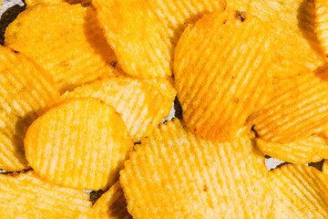 Background of potato crisps close-up. The texture of the corrugated crisps. Top view