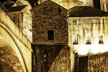 Antique stone houses illuminated in Mostar, Bosnia and Herzegovina at night . Stari Most, with...