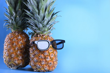 Pineapple in sunglasses close-up on blue background