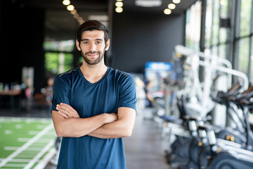 Healthy caucasian man standing with smart, healthy, freshness and active pose in the gym. Exercise, workout, muscle training, weight lifting, weight loss, heart rate practice and diet concept.