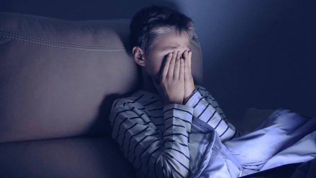 Tired boy using tablet pc at home at night. The childs eyes hurt because he playing computer games, watching video, surf on net for a long time