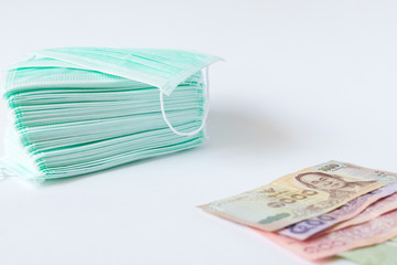 A pile of green surgical protective face mask with coin and money on isolated white backgroud. Concept during Corona virus outbrek in China, shortage of face mask increase the demand in higher price.