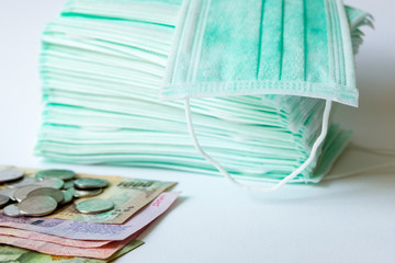 A pile of green surgical protective face mask with coin and money on isolated white backgroud. Concept during Corona virus outbrek in China, shortage of face mask increase the demand in higher price.