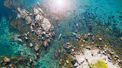 Plakat 岩礁の間を抜けるパドラー 海面に反射する太陽 空撮