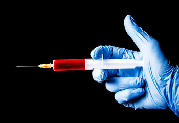 Virus vaccine research background. Syringe isolated on black. Blood test clinic. Blue latex glove...