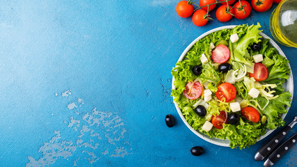  Lettuce, cheese, olives, onion and cherry tomatoes on a plate. Healthy and diet food concept. Top...