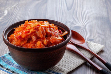 Braised cabbage with tomatoes on an old wooden background in rustic style