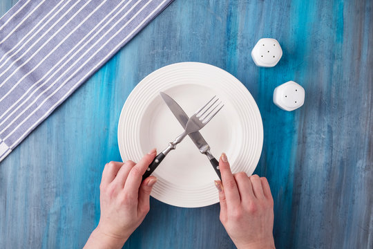 Female hands holding fork and knife over .white plate. Woman on diet.