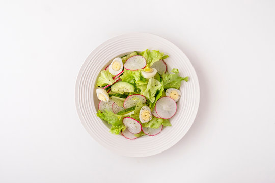 Healthy vegetables salad with cucumbers, quaill eggs and radish. Fresh vegetables salad isolated on white background. Top view, text space