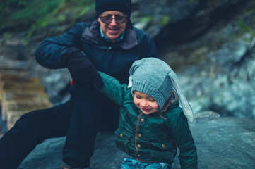 Preschooler and his grandfather sitting on a rock in winter