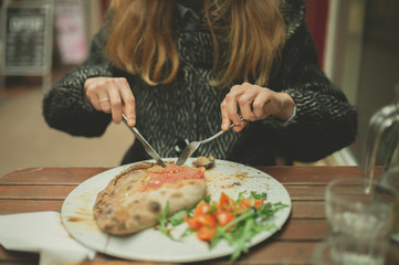 Young woman eating calzone pizza in the winter