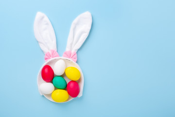 Cute Easter composition. Multicolored easter eggs and bunny ears on blue background. Top view. Copy space