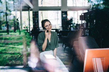 Pleased woman speaking on smartphone office
