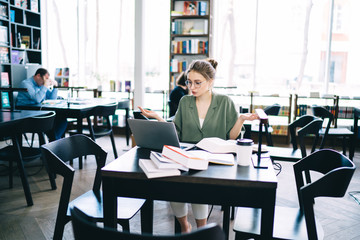 Surprised student sitting and focusing on laptop at library