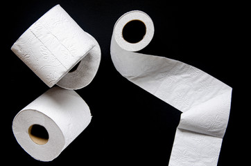 Rolls of white toilet paper lie on a black background