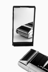 An Electric Shaver on the white background in fron of mirror and focus on the mirror reflection.