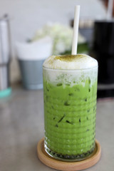 Green tea with milk, milk foam and green tea powder. Sprinkle in a serving glass with ice in a saucer.
