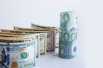 Curved US Dollar Banknotes on the white background with standing and rolled Euro banknotes.