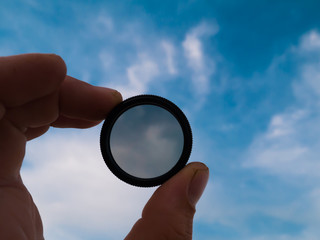 Llight filter in hand against sky background