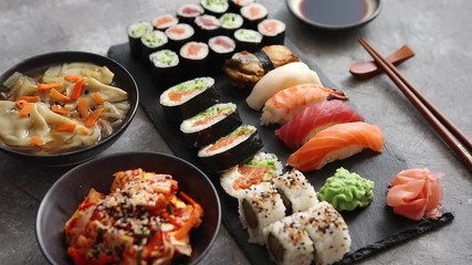 Composition of different kinds of sushi rolls placed on black stone board - Powered by Adobe